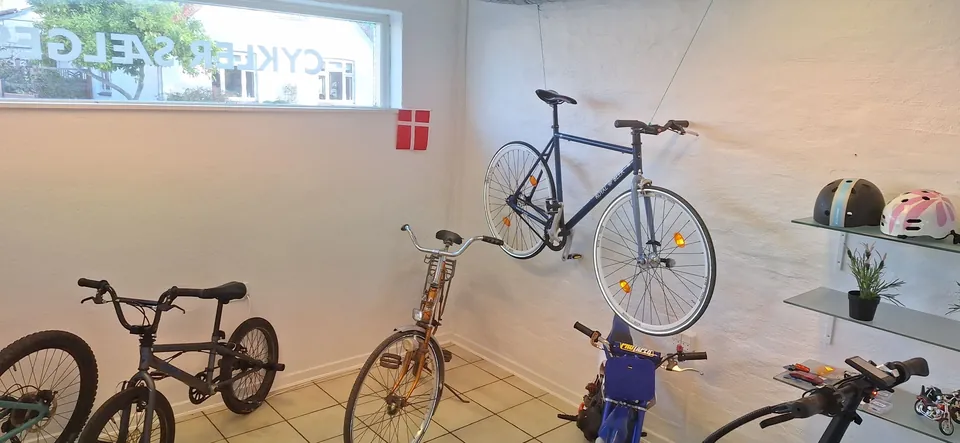 Racercykel på væggen og vinduet med Cykler sælges i MT Bike